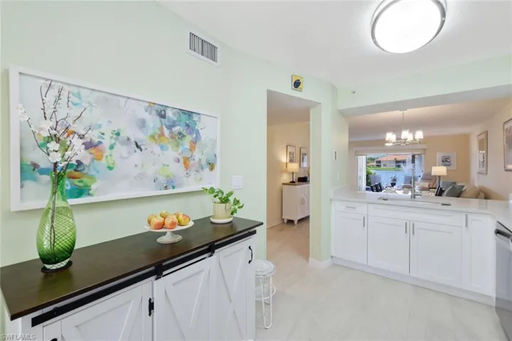 Kitchen featuring sink, an inviting chandelier, white cabinetry, and light tile floors