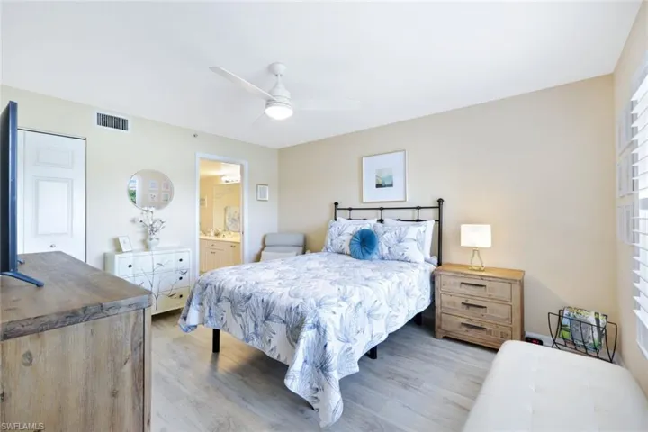 Bedroom with ceiling fan, light hardwood / wood-style floors, and connected bathroom
