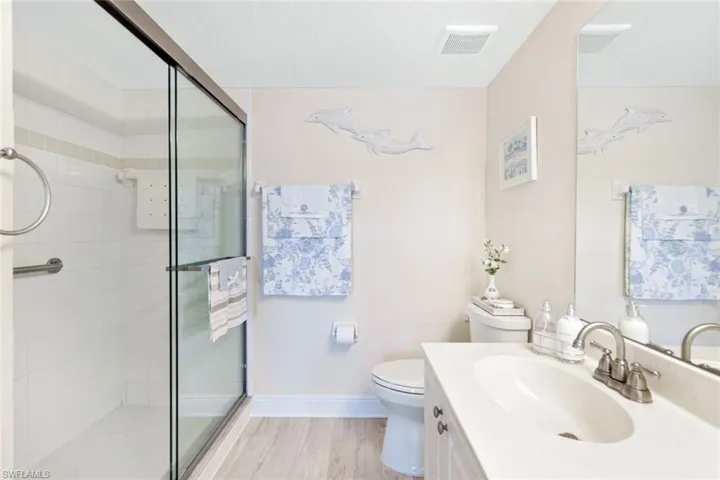 Bathroom featuring toilet, walk in shower, vanity, and hardwood / wood-style flooring