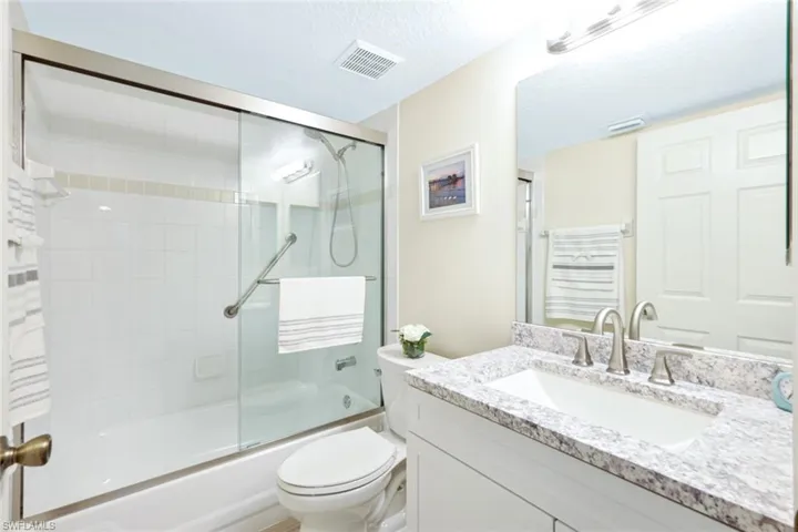 Full bathroom with enclosed tub / shower combo, a textured ceiling, toilet, and vanity