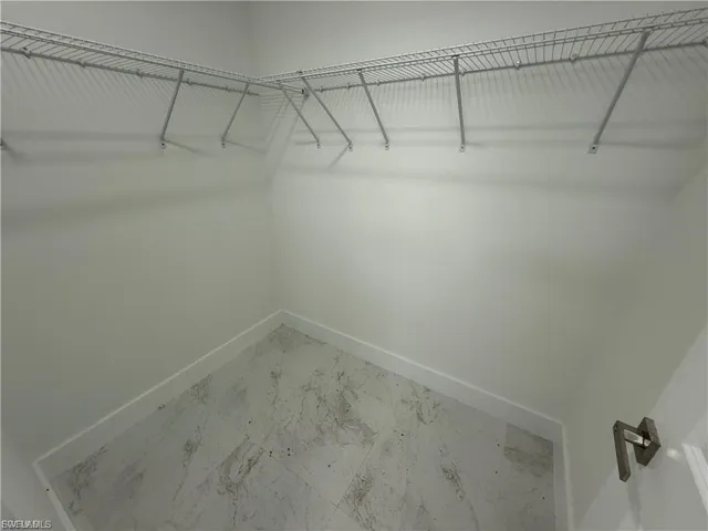 Walk in closet featuring marble finish floors
