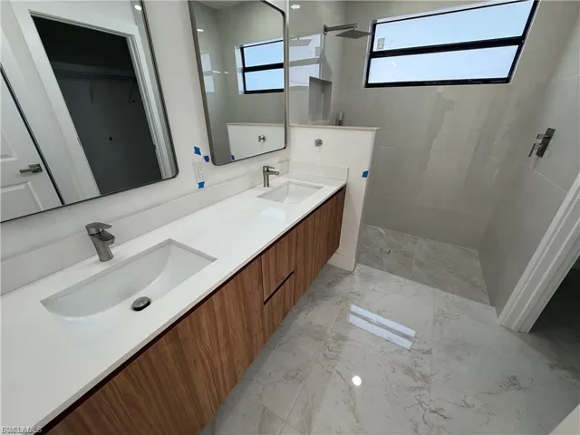 Bathroom featuring double vanity, a spacious closet, and walk in shower
