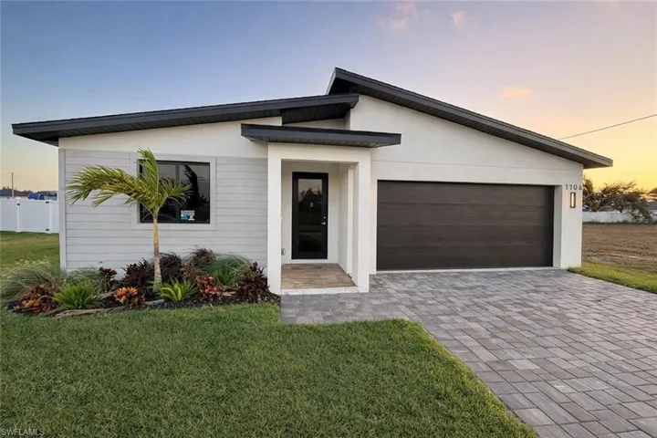 Modern home with a front lawn, driveway, stucco siding, and an attached garage