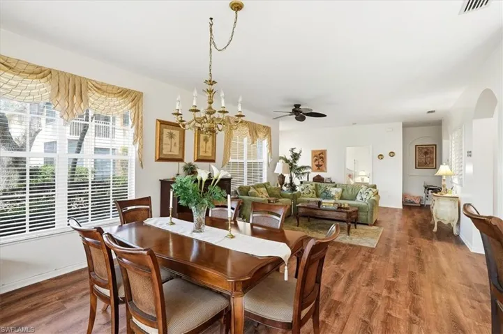 Dining space with a ceiling fan, wood finished floors, a chandelier, and arched walkways