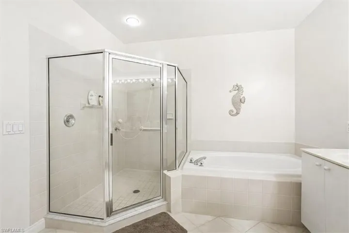 Full bath featuring vanity, a garden tub, a shower stall, and light tile patterned flooring