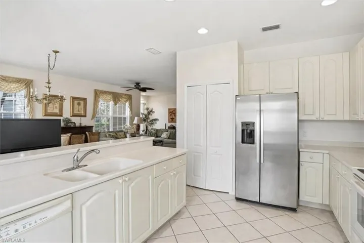 Kitchen featuring stainless steel fridge, light countertops, white dishwasher, decorative light fixtures, and open floor plan