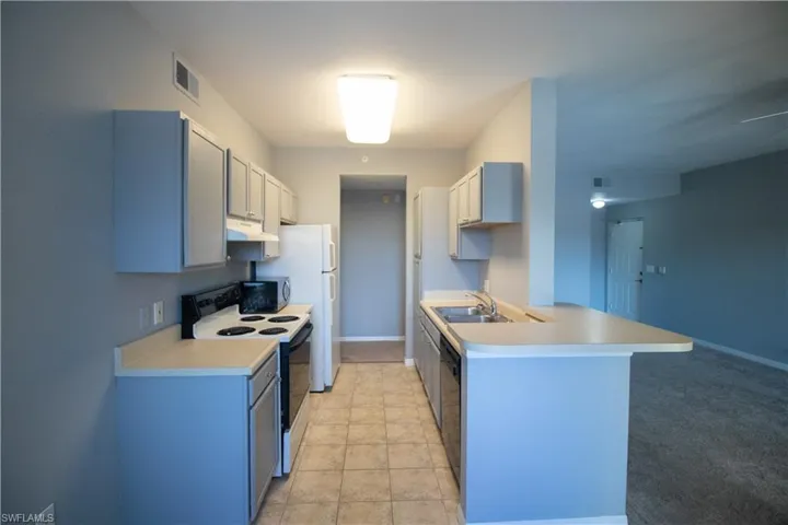 Kitchen featuring sink, light colored carpet, and white appliances