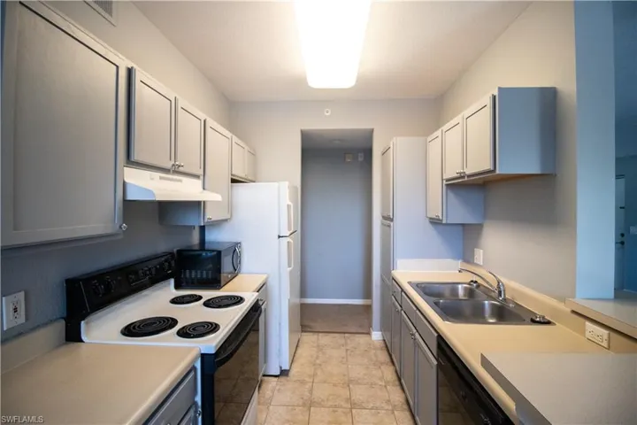 Kitchen with dishwasher, sink, gray cabinets, light tile patterned flooring, and white electric range