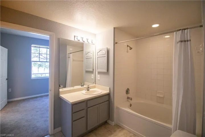 Bathroom with vanity, a textured ceiling, and shower / bath combination with curtain