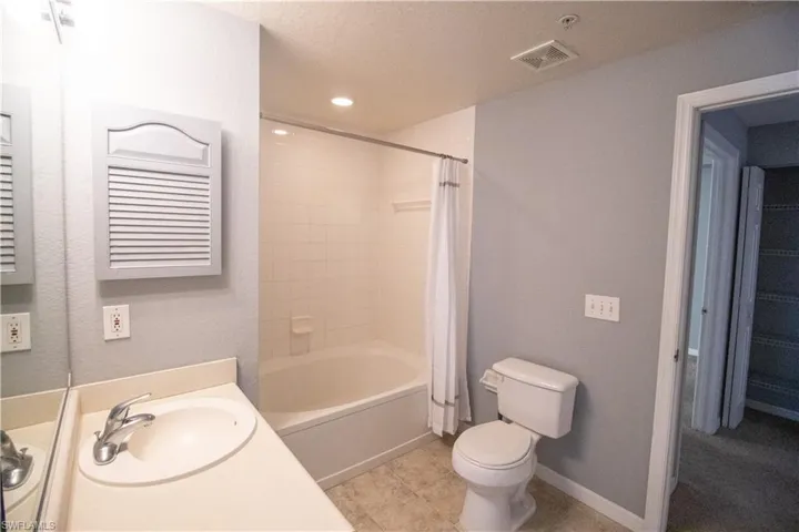 Full bathroom featuring shower / bathtub combination with curtain, a textured ceiling, tile patterned floors, toilet, and vanity