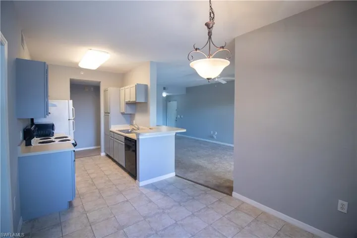 Kitchen with white appliances, a chandelier, light tile patterned floors, hanging light fixtures, and sink