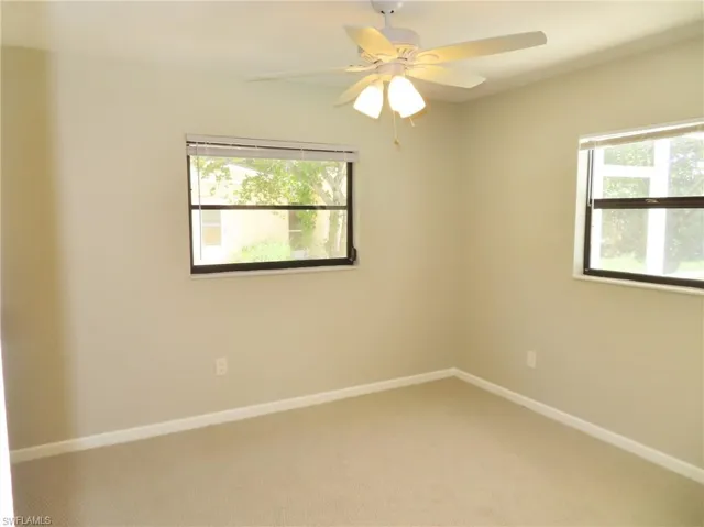 Carpeted spare room featuring plenty of natural light and ceiling fan