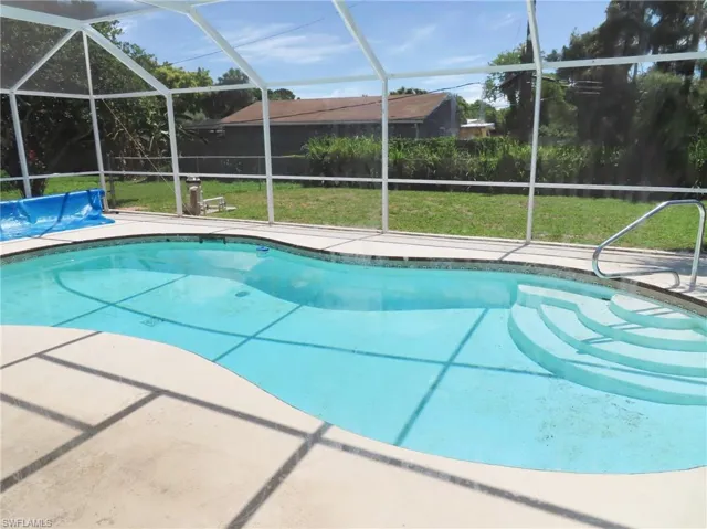 View of pool with a yard and glass enclosure