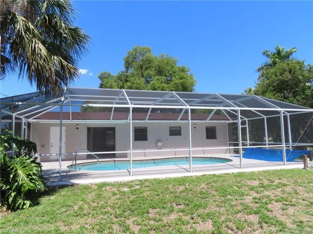 View of pool with glass enclosure and a yard