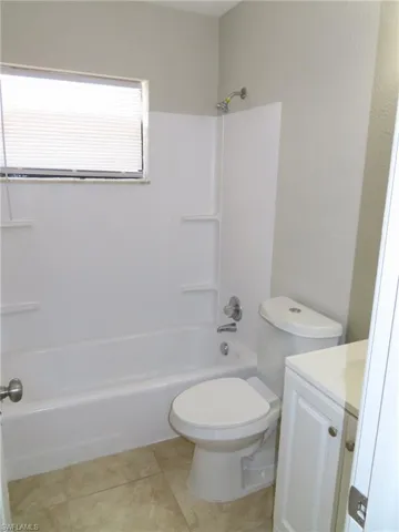 Full bathroom featuring shower / tub combination, vanity, toilet, and tile flooring