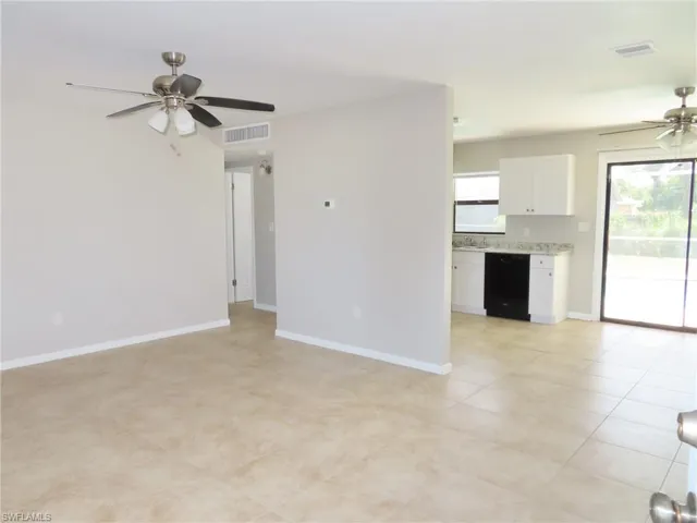 Unfurnished living room with sink, ceiling fan, and light tile floors