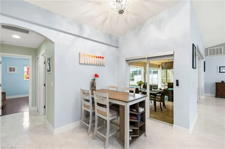 Dining space featuring arched walkways, vaulted ceiling, light tile patterned flooring, and recessed lighting