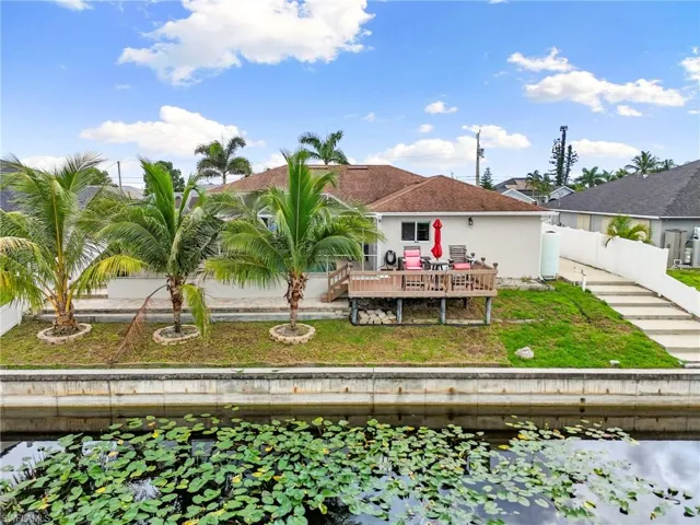 Rear view of property featuring a deck with water view, a fenced backyard, and stucco siding
