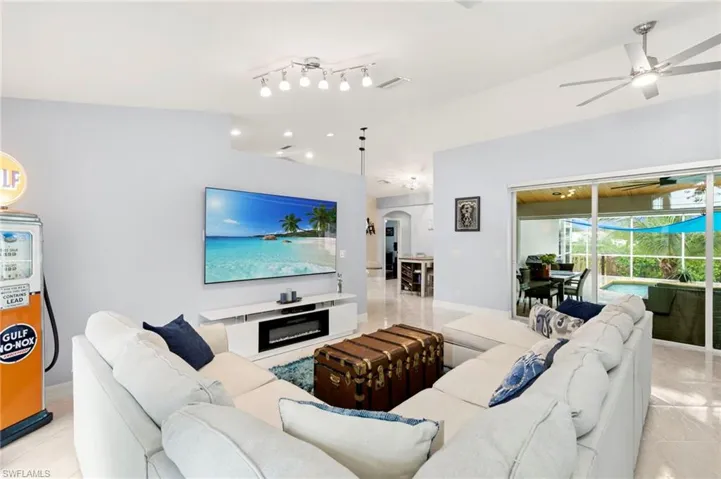 Living area featuring light tile patterned flooring, arched walkways, and a ceiling fan