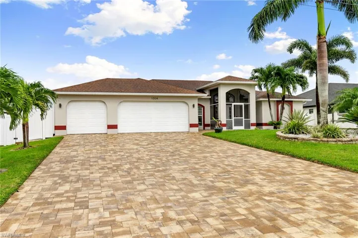 Mediterranean / spanish-style home with decorative driveway, stucco siding, a garage, a front yard, and roof with shingles