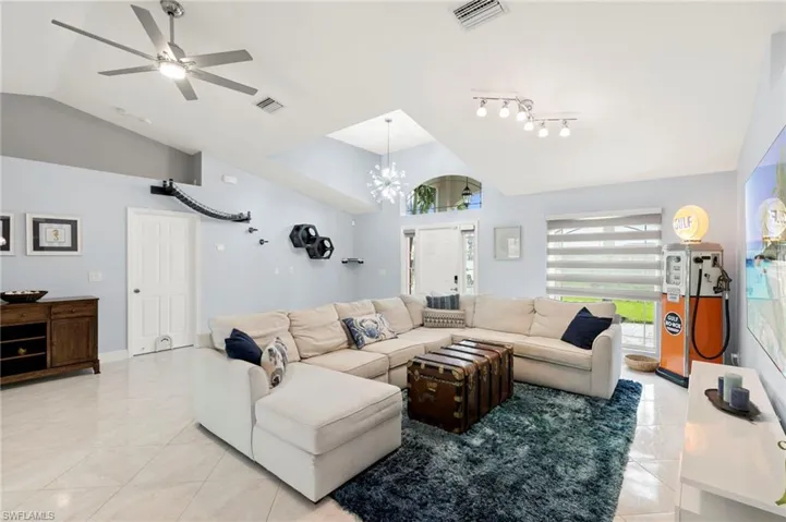 Living area with lofted ceiling, ceiling fan, a chandelier, and light tile patterned floors