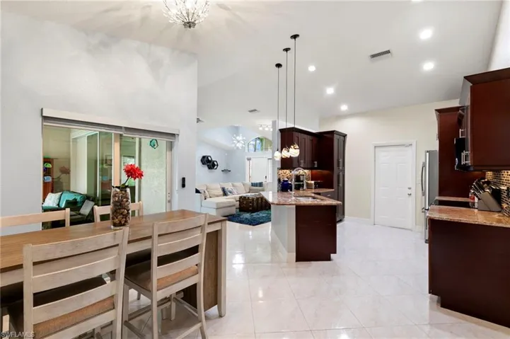 Kitchen featuring a chandelier, open floor plan, dark brown cabinets, light stone counters, and recessed lighting