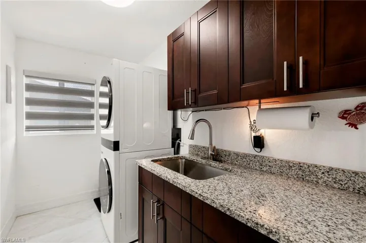 Laundry area featuring stacked washer / drying machine and cabinet space