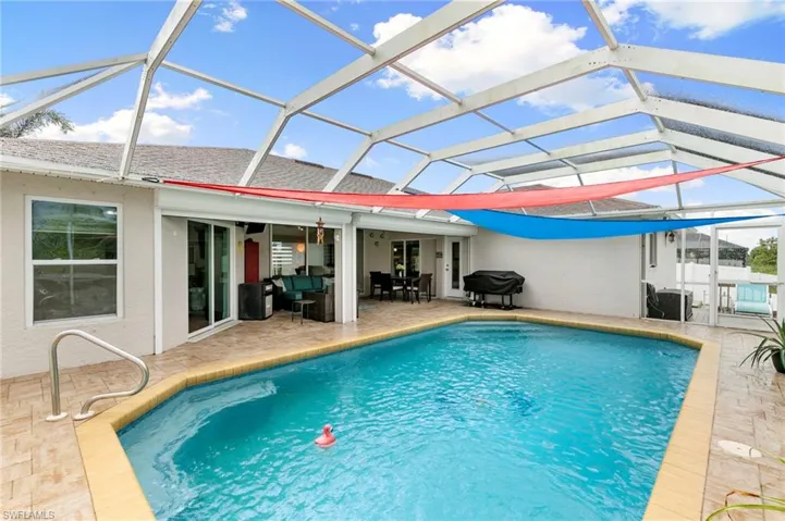 Outdoor pool featuring a patio, glass enclosure, and outdoor dining area