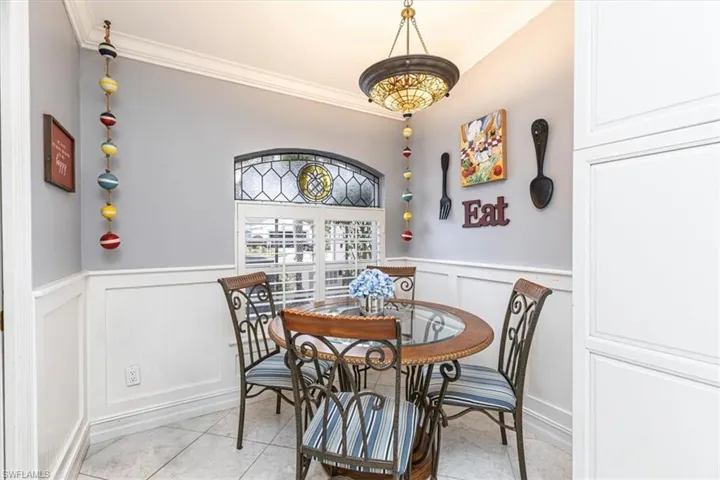 Dining room featuring ornamental molding, wainscoting, tile patterned floors & decorative walls.