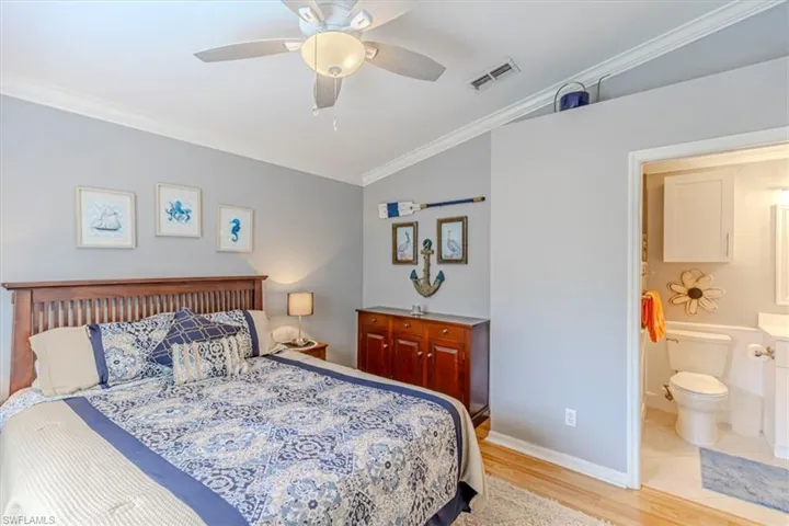 Guest Bedroom featuring crown molding, light wood finished floors, vaulted ceiling & ceiling fan.