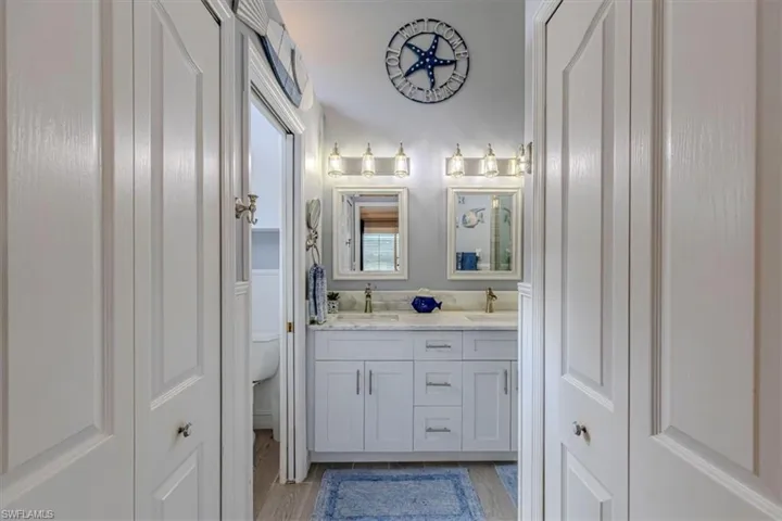 Primary bathroom featuring double vanity, a closet & light wood-style flooring