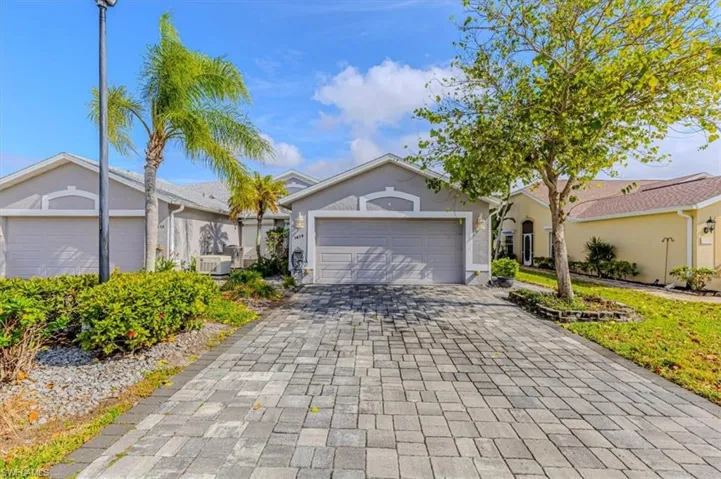Single story home with stucco siding, decorative paver driveway, and a 2 car garage.