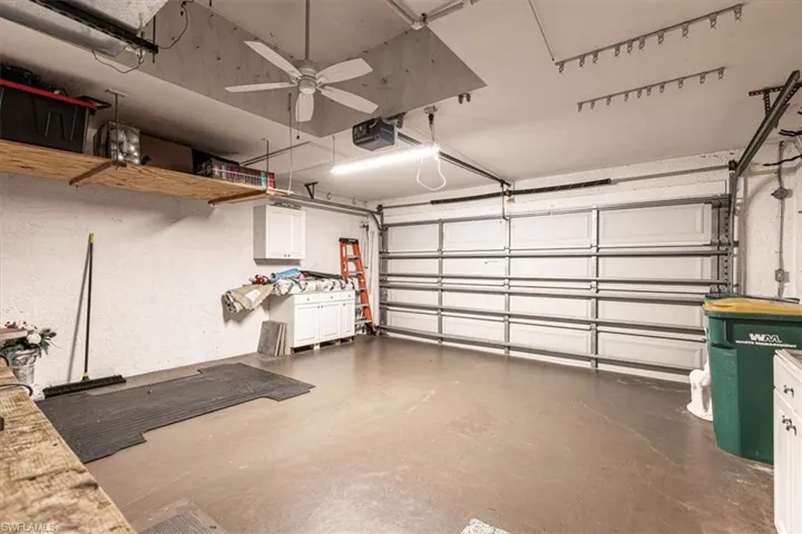 Garage with a garage door opener, ceiling fan & light.
