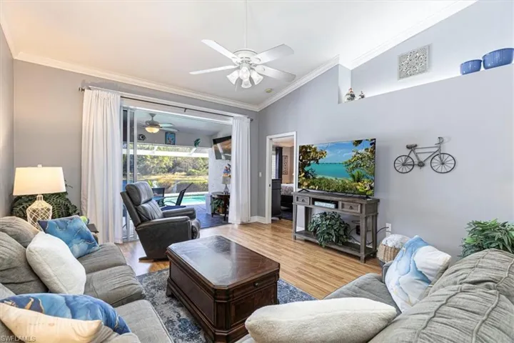 Living area featuring ceiling fan, crown molding, wood finished floors & vaulted ceiling.