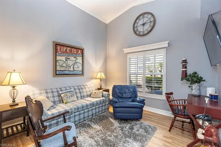 Den area with light wood-style flooring & crown molding.