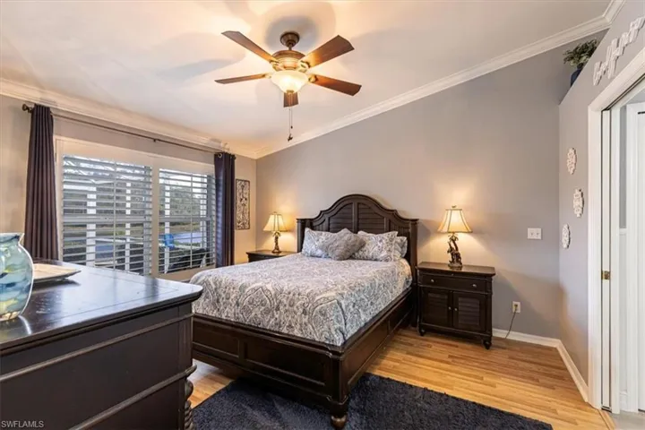 Primary Bedroom w/ ornamental molding, light wood-style floors & ceiling fan.
