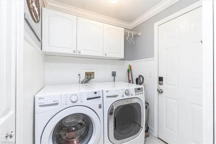 Laundry room with cabinet space, wainscoting, crown molding & washer and dryer.