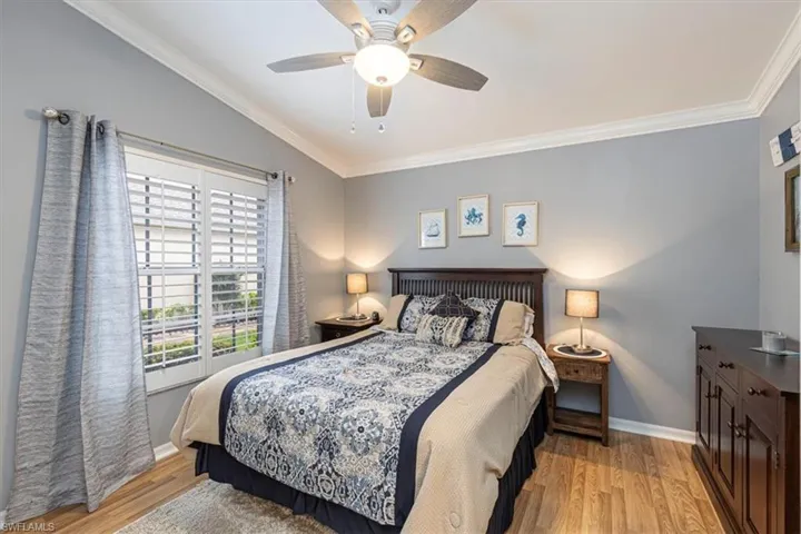 Guest Bedroom w/ crown molding, light wood-style flooring & ceiling fan.