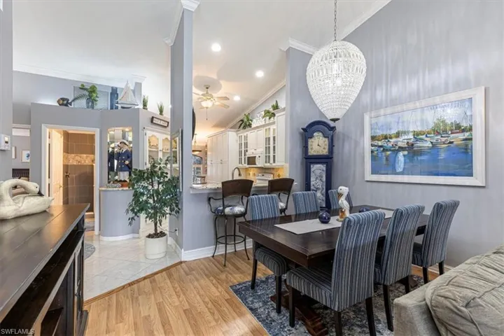 Dining area featuring ornamental molding, recessed lighting, ceiling fan, light wood-style floors & chandelier.