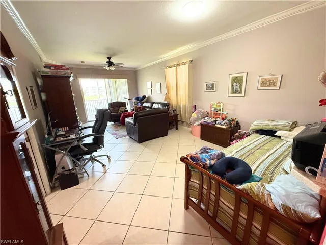 Living room with crown molding, light tile patterned floors, and ceiling fan