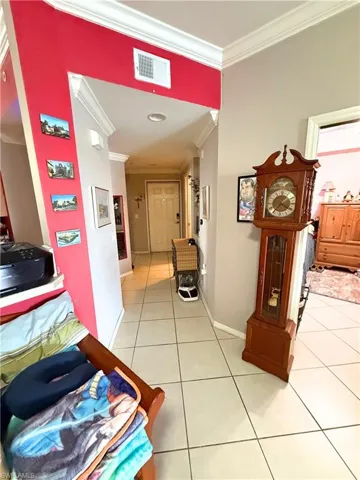 Hall with crown molding and light tile patterned flooring