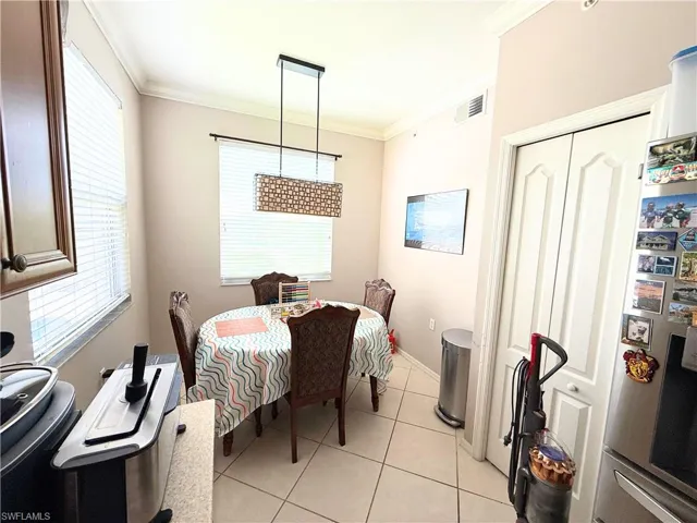 Dining area with ornamental molding and light tile patterned flooring