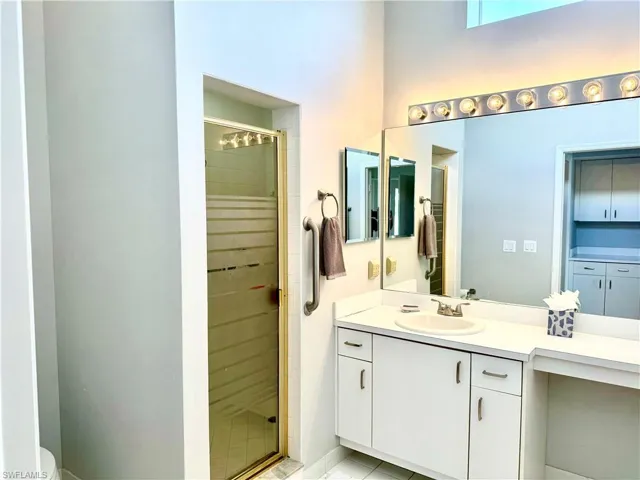 Bathroom featuring tile patterned floors, an enclosed shower, vanity, and toilet