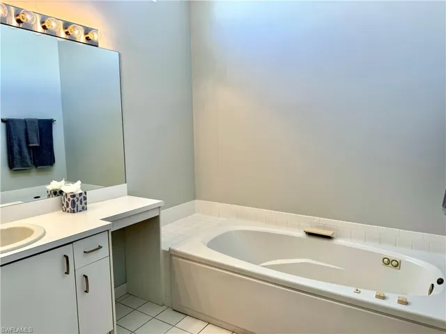 Bathroom with a tub to relax in, vanity, and tile patterned floors