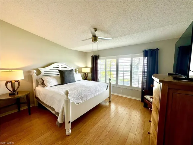 Bedroom featuring a textured ceiling, light hardwood / wood-style floors, and ceiling fan