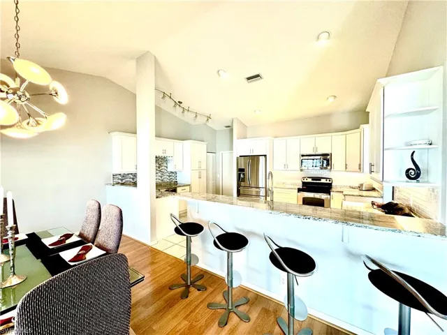 Kitchen featuring white cabinets, vaulted ceiling, appliances with stainless steel finishes, and light wood-type flooring