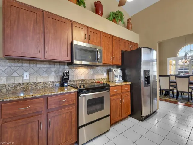 Kitchen featuring tasteful backsplash, light stone countertops, appliances with stainless steel finishes, and light tile patterned floors