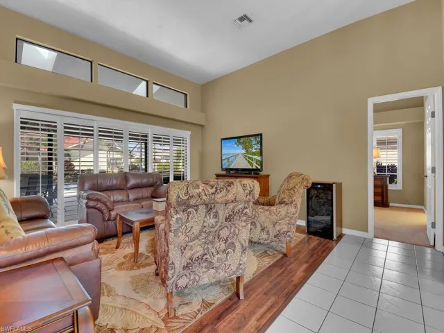 Living room featuring a towering ceiling, light tile patterned floors, and beverage cooler