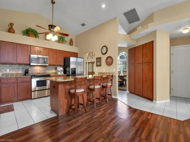 Kitchen with light tile patterned floors, stainless steel appliances, a center island, and a kitchen bar