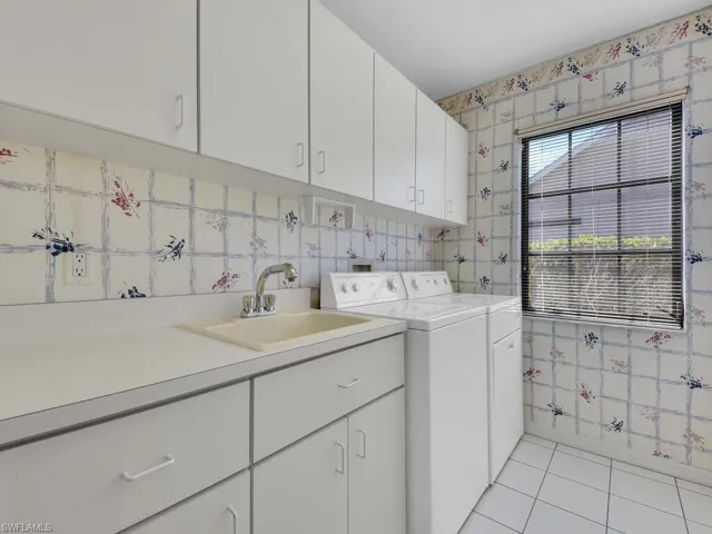 Laundry area with cabinets, separate washer and dryer, sink, and light tile patterned floors